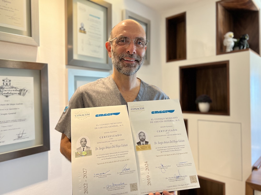 Dr. Del Hoyo in front of his awards carrying his 2019-2024 and 2022-2027 El Consejo Mexicano De CirugÃ­a General, A.C. Certificado
